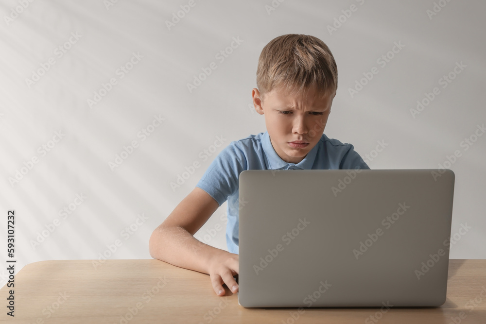 Upset boy with laptop at table, space for text. Cyber bullying Upset boy with laptop at table, space for text. Cyber bullying