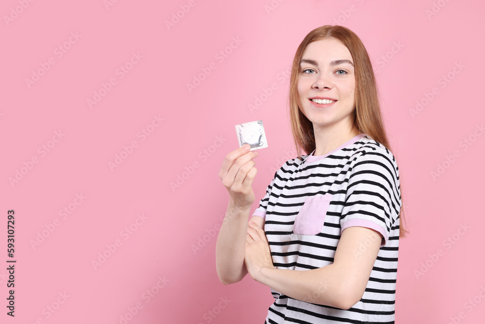 Woman holding condom on pink background, space for text. Safe sex Woman holding condom on pink background, space for text. Safe sex