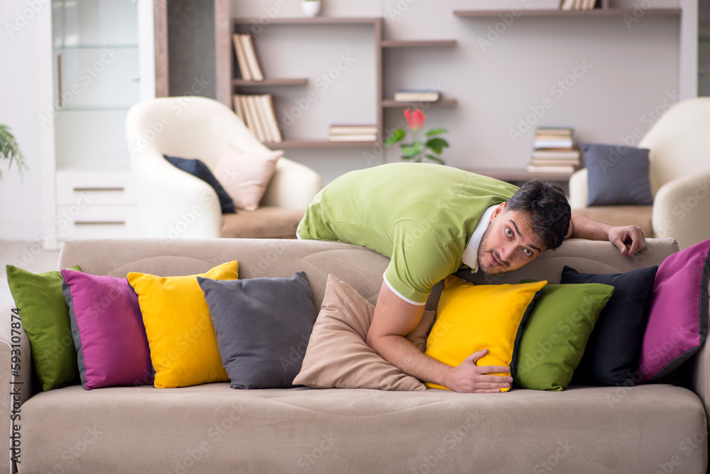 Obraz premium Young man with a lot of pillows sitting on the sofa