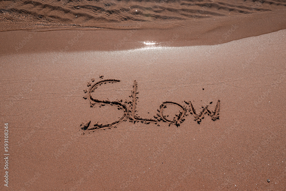 Fototapeta premium slow mindfulness concept written on sand