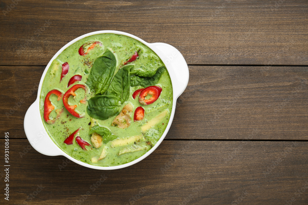 Saucepan with delicious green curry chicken soup on wooden table, top view. Space for text Saucepan with delicious green curry chicken soup on wooden table, top view. Space for text