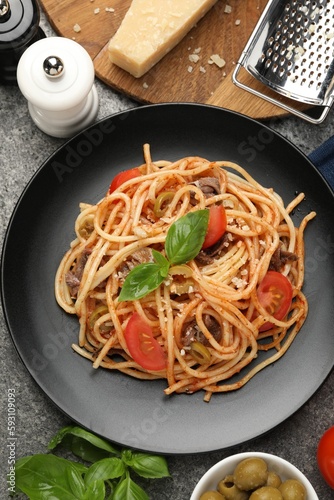 Delicious pasta with anchovies, tomatoes and olives on grey table, flat lay