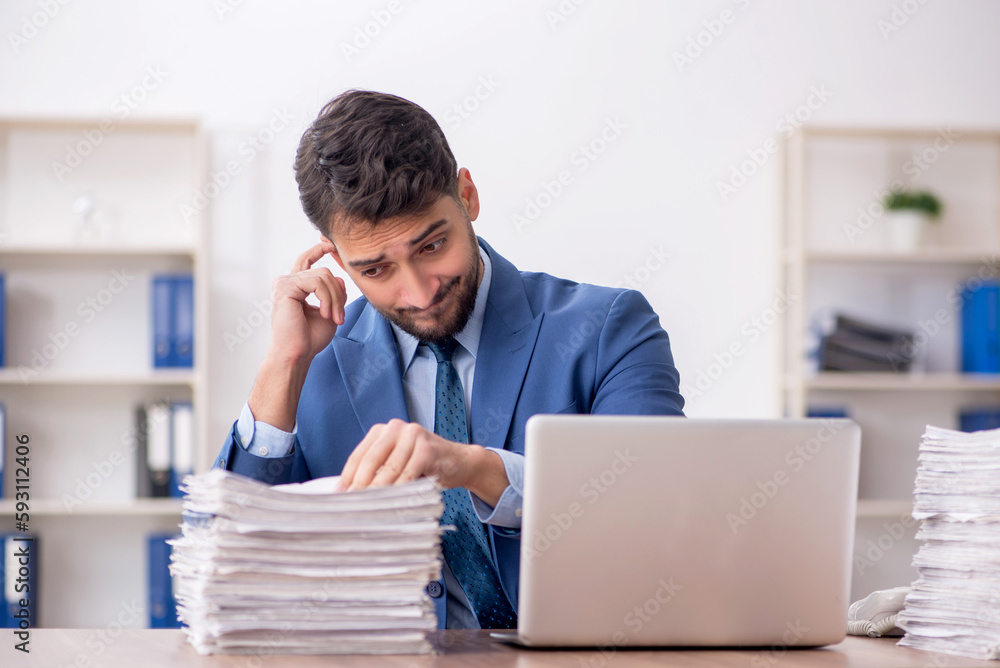 Young male employee and too much work in the office Young male employee and too much work in the office