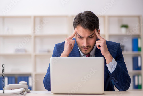 Young male employee sitting at workplace