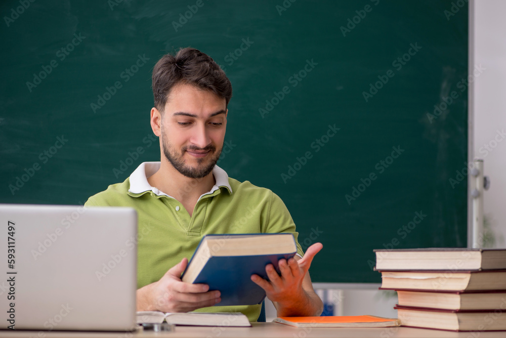 Young male student sitting in front of green board Young male student sitting in front of green board