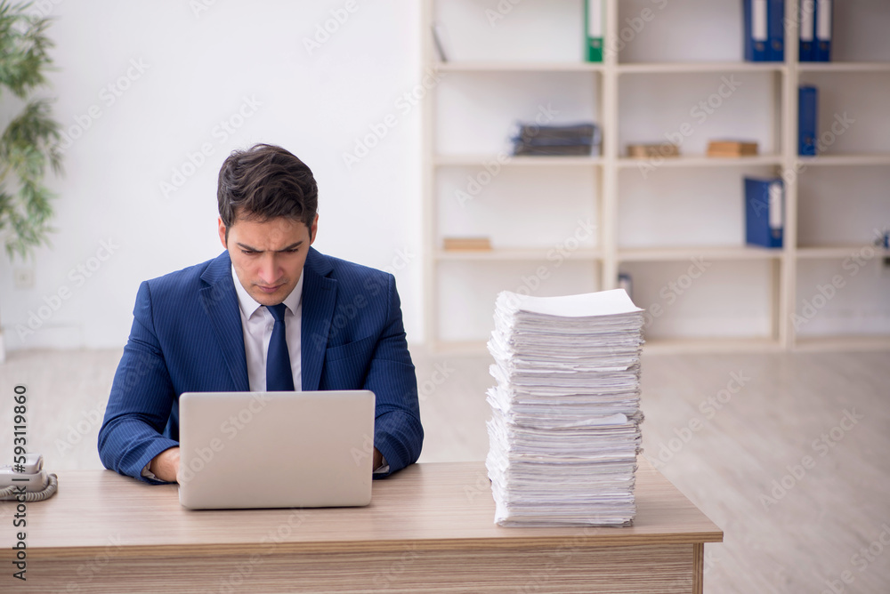 Young male employee and too much work in the office Young male employee and too much work in the office