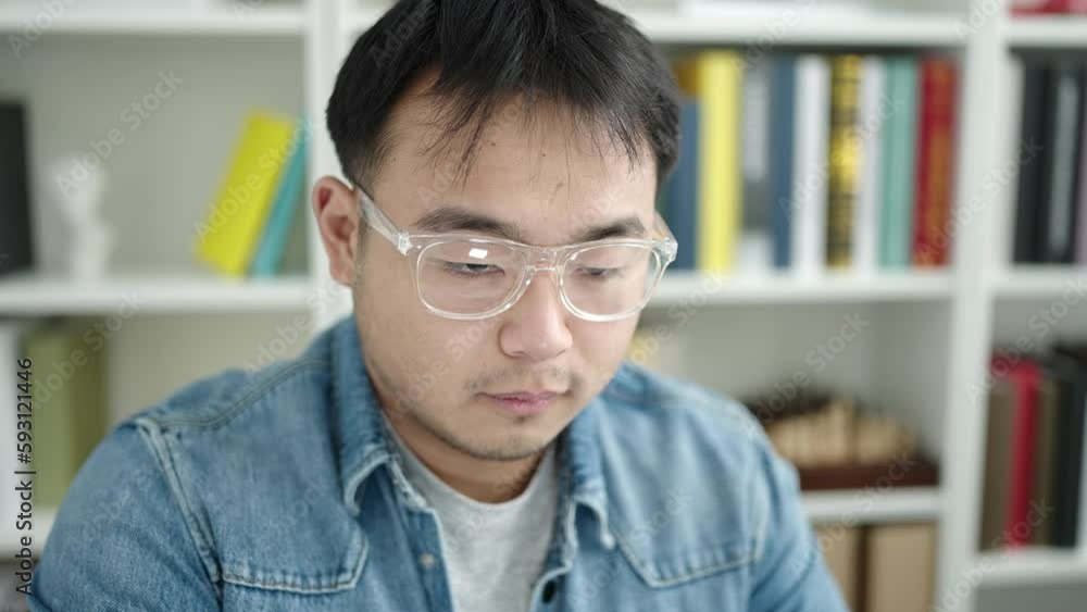 Young chinese man student using computer stressed at library university Young chinese man student using computer stressed at library university