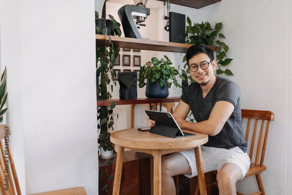 Happy freelance asian man working in the cafe with his tablet. Happy freelance asian man working in the cafe with his tablet.