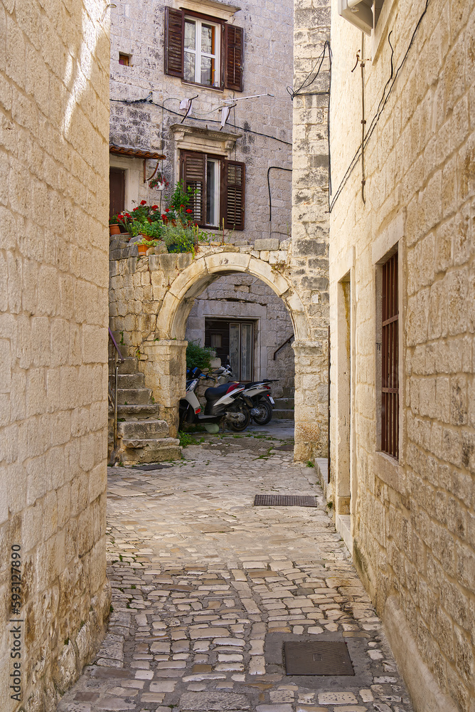 Narrow street with stone houses. Old houses and old narrow alley in Trogir, Croatia, Europe. Streets in old town.