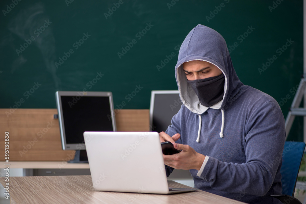 Young male hacker sitting in the classroom