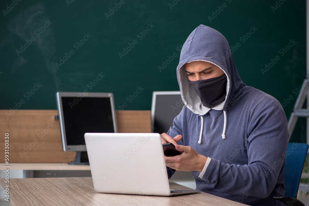 Young male hacker sitting in the classroom Young male hacker sitting in the classroom