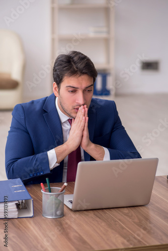 Young male employee unhappy with excessive work in the office