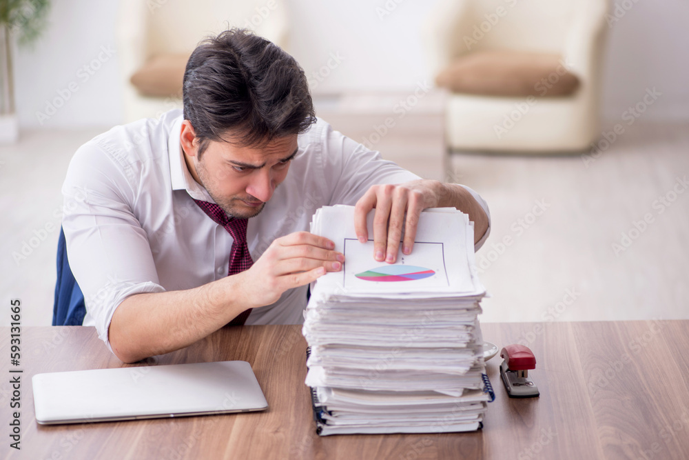 Young male employee unhappy with excessive work in the office Young male employee unhappy with excessive work in the office