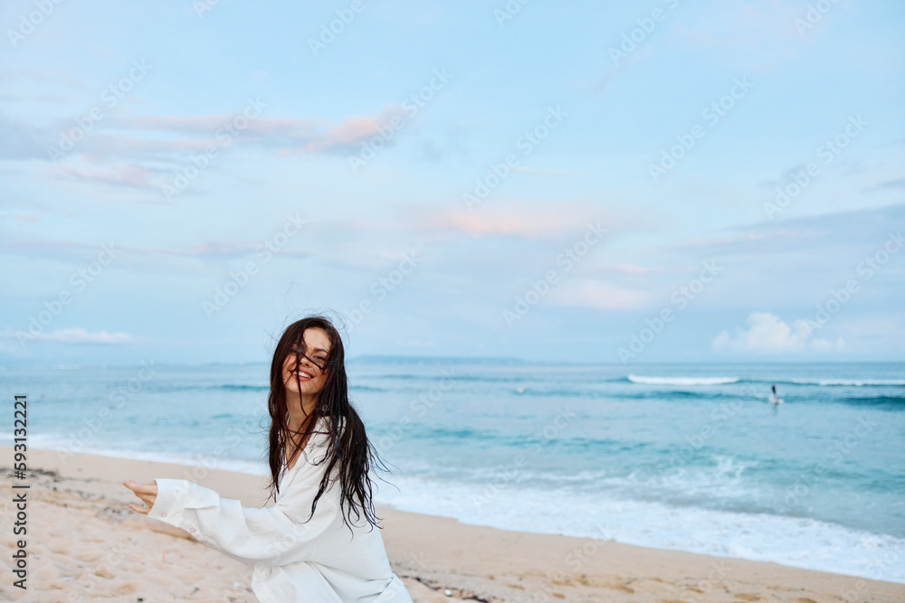 Brunette woman with long hair in a white shirt and denim shorts smile and happiness running on the beach and having fun smile with teeth in front of the ocean, vacation summer trip Brunette woman with long hair in a white shirt and denim shorts smile and happiness running on the beach and having fun smile with teeth in front of the ocean, vacation summer trip