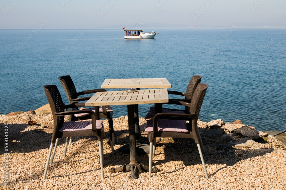 An empty table with four chairs by the blue sea