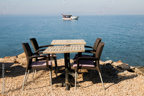 An empty table with four chairs by the blue sea © Gulsen