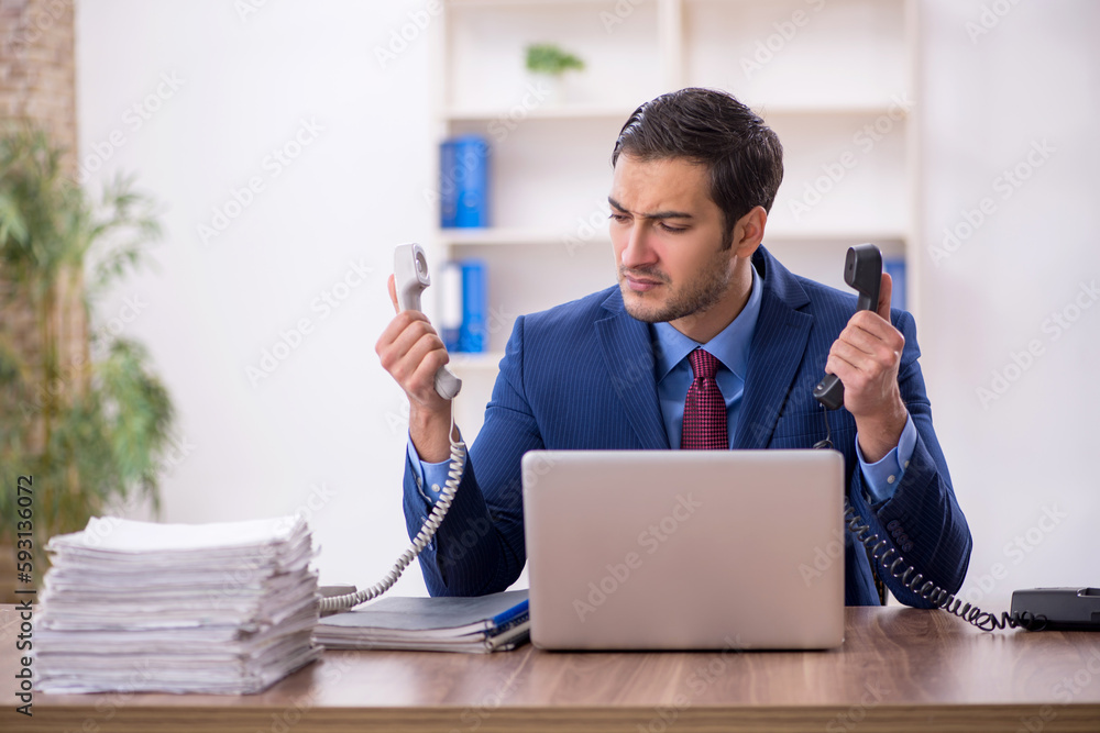 Young male employee and too much work in the office Young male employee and too much work in the office
