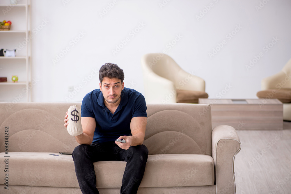 Young man holding moneybag at home Young man holding moneybag at home