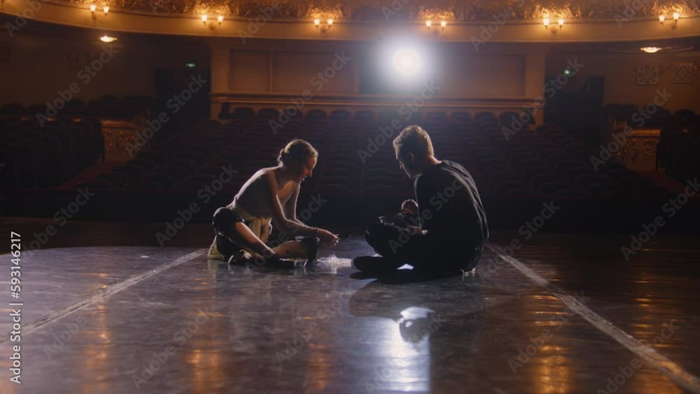 Vidéo Stock Pair of tired ballet dancers sit on theatre stage after ...