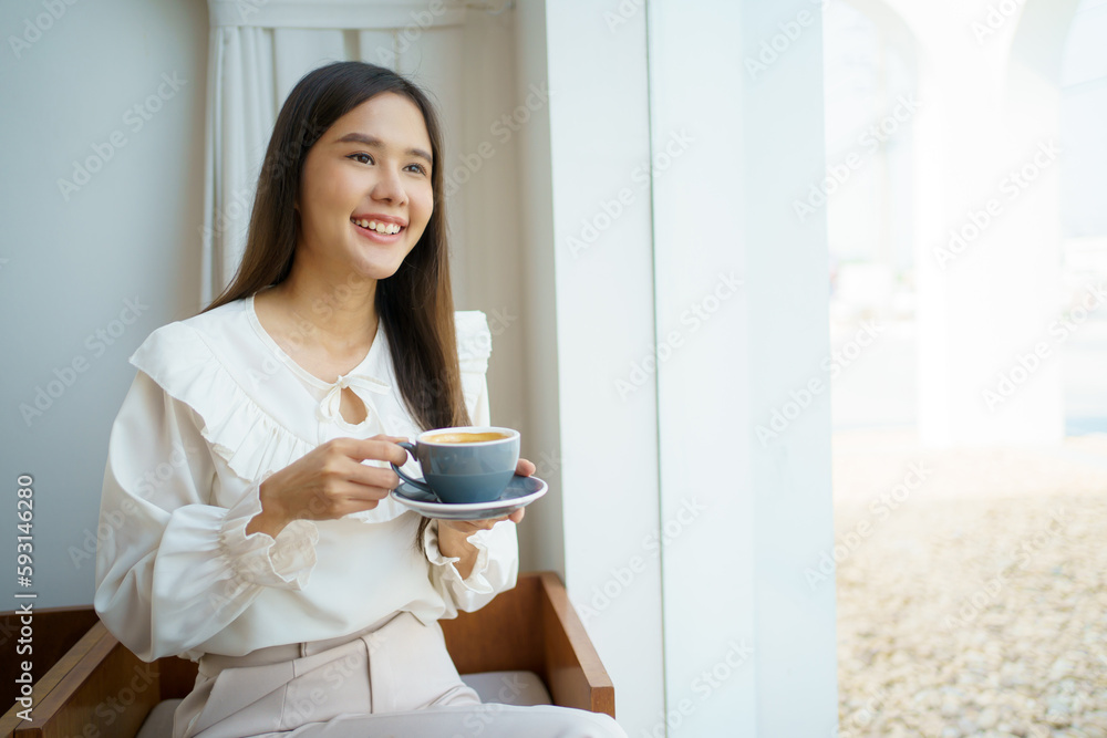 Asian businesswoman holding a coffee cup on hand during relaxing in the coffee shop. Asian smart and good looking businesswoman taking a break in coffee shop. Asian businesswoman holding a coffee cup on hand during relaxing in the coffee shop. Asian smart and good looking businesswoman taking a break in coffee shop.