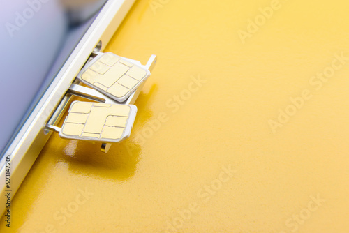 Broadband 5G mobile communication technology concept : SIM card tray / dual SIM card slot with two nano SIM cards on yellow background. SIM stores international mobile subscriber identity IMSI number. photo