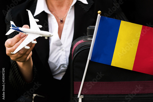 business woman holds toy plane travel bag and flag of Romania