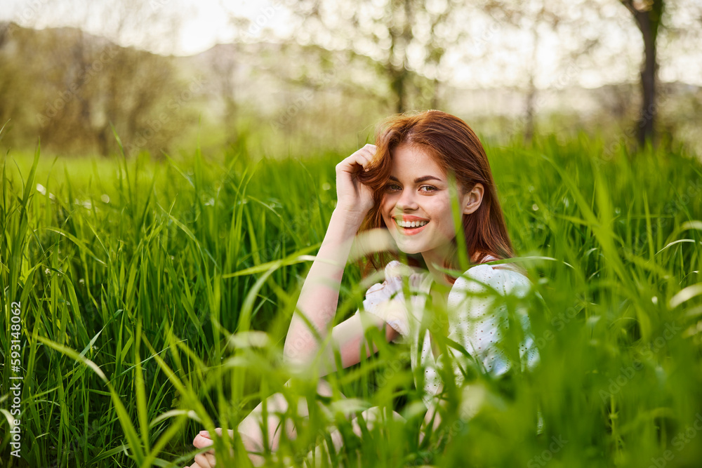 a young woman sitting resting in the tall grass straightening her hair a young woman sitting resting in the tall grass straightening her hair