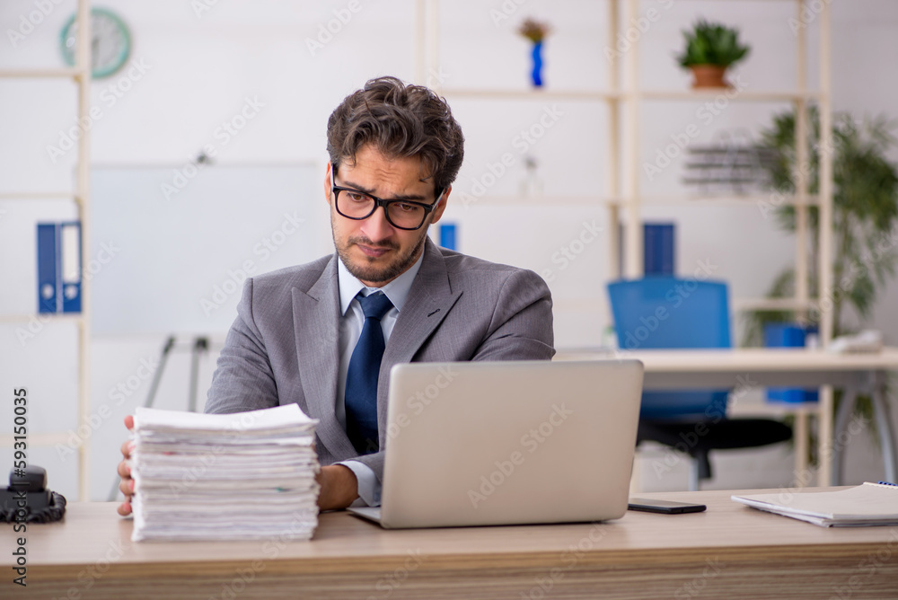 Young male employee sitting at workplace Young male employee sitting at workplace