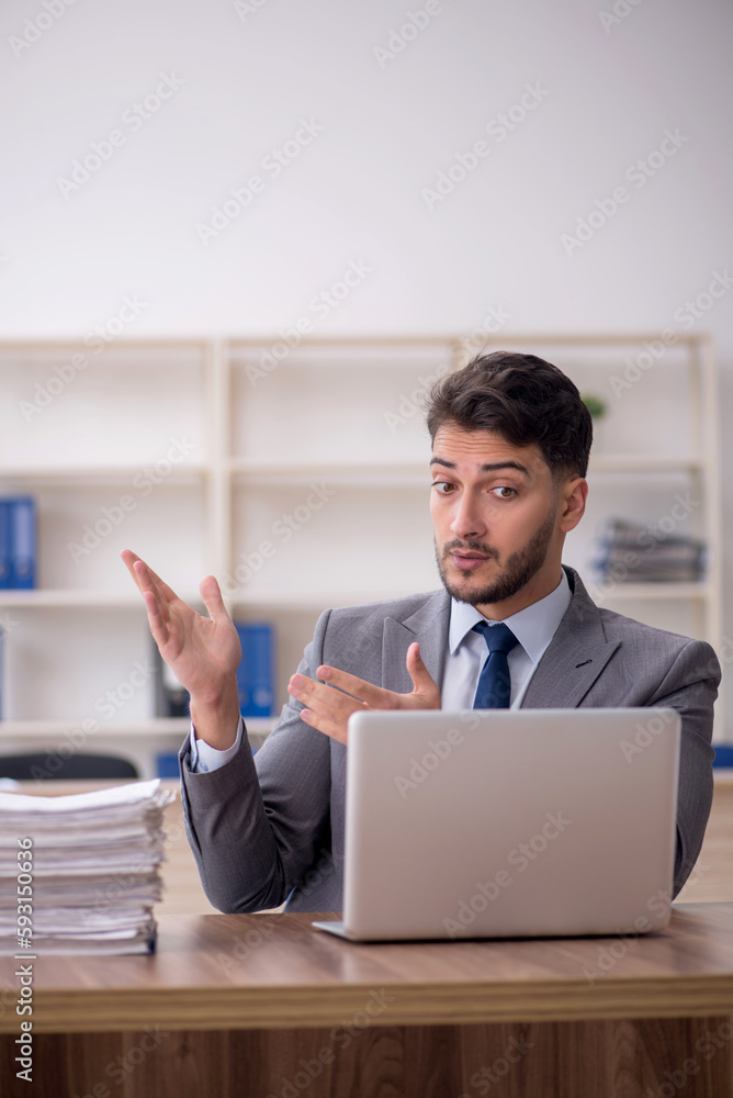 Young male employee and too much work in the office Young male employee and too much work in the office
