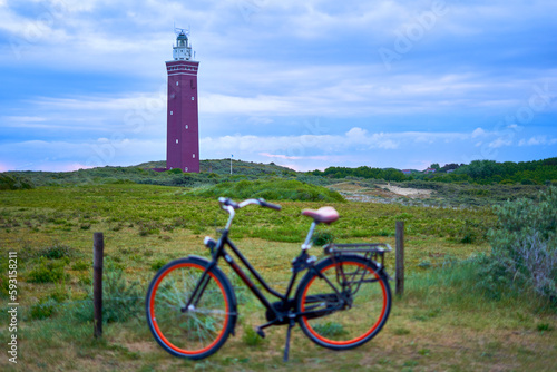 Dutch lighthouse on green heath. ladies bike out of focus. Landscape at dawn. Netherlands, Zuid-Holland, Goeree-Overflakkee, Ouddorp.