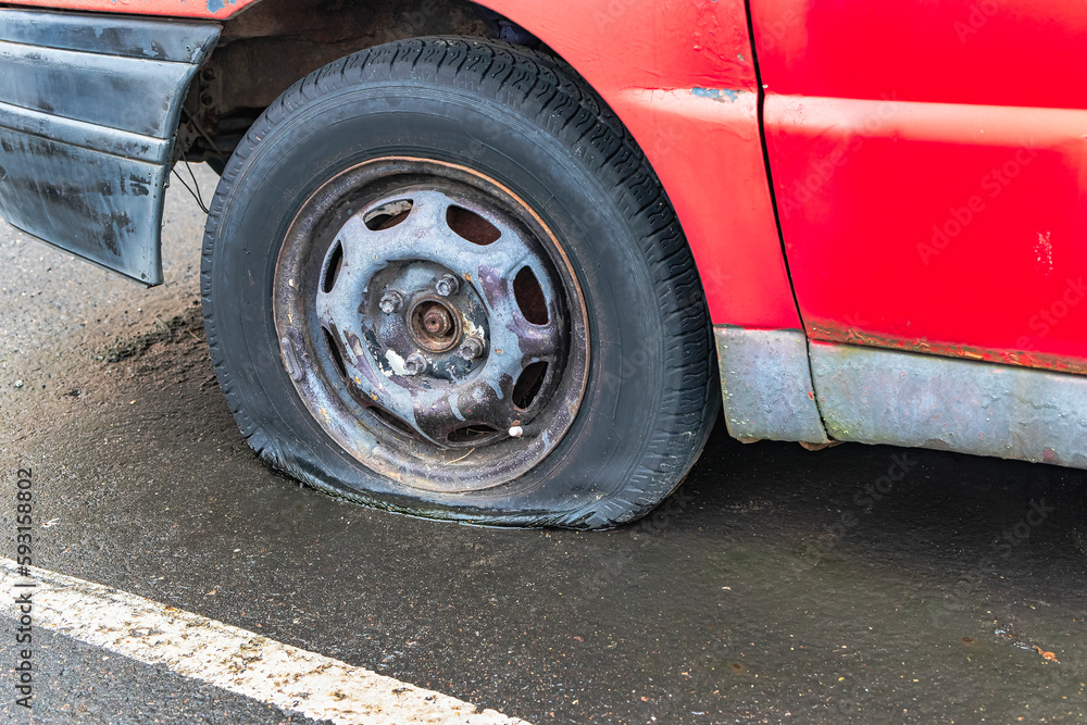 flat car tire close up, punctured wheel. A punctured tire while traveling by car. Replacing a punctured wheel.