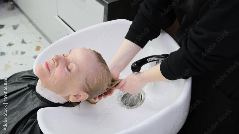 hairdresser wash head to the elderly woman in the salon. hairdresser wash head to the elderly woman in the salon.