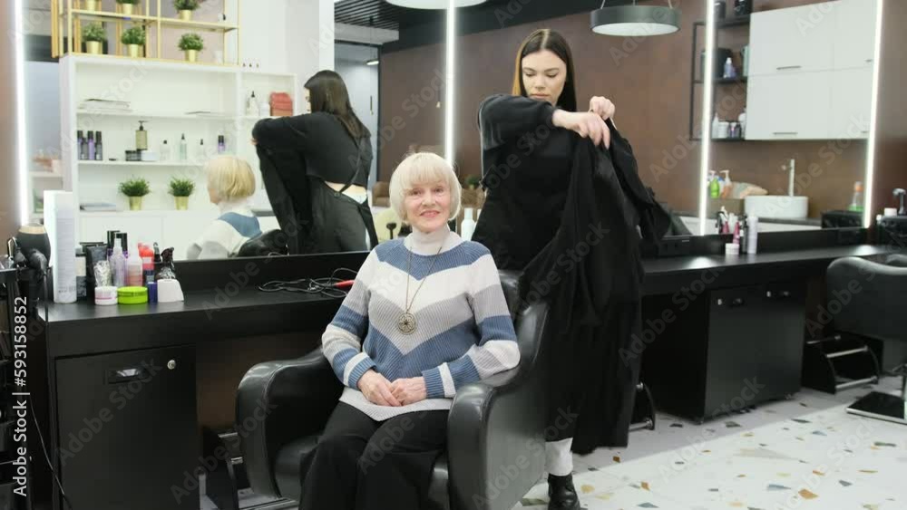 A hairdresser prepares an elderly client for a haircut. A hairdresser prepares an elderly client for a haircut.