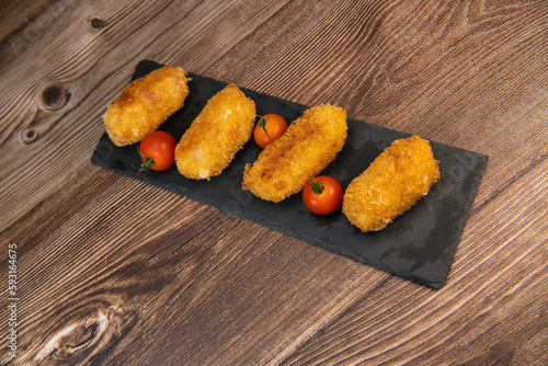 Homemade traditional Spanish croquettes or croquetas on a black plate with fork, Tapas food, High quality photo