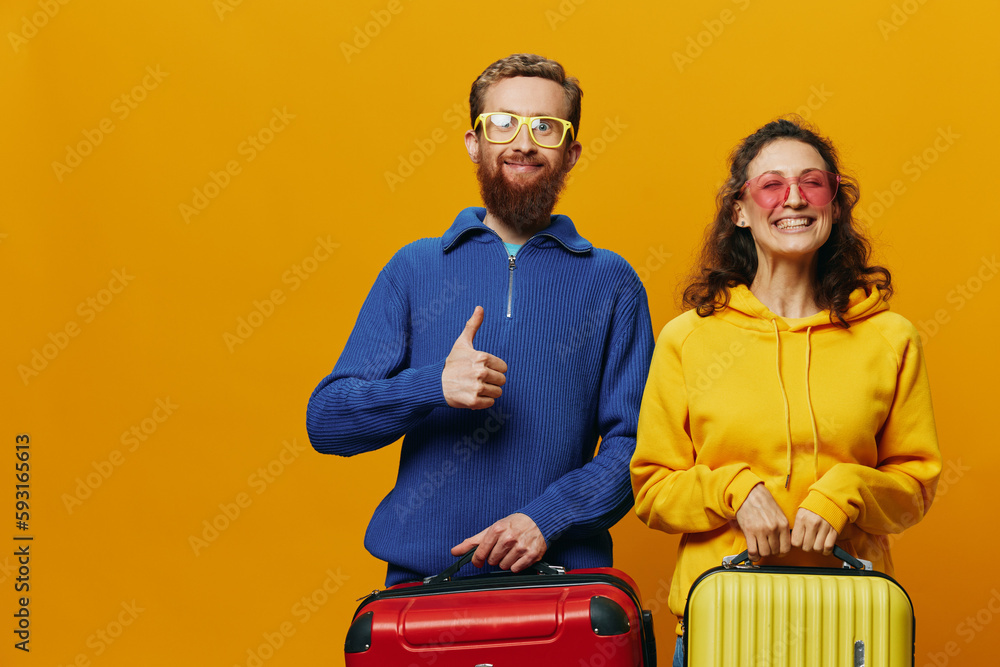 Woman and man smiling, suitcases in hand with yellow and red suitcase smiling merrily and crooked, yellow background, going on a trip, family vacation trip, newlyweds. Woman and man smiling, suitcases in hand with yellow and red suitcase smiling merrily and crooked, yellow background, going on a trip, family vacation trip, newlyweds.