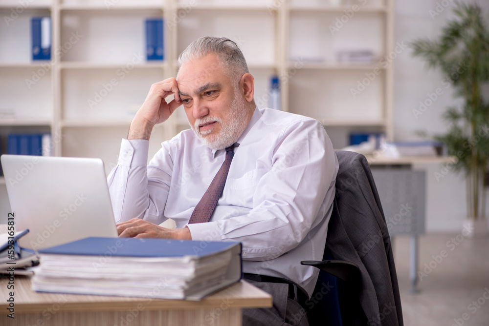 Fototapeta premium Old male employee working in the office