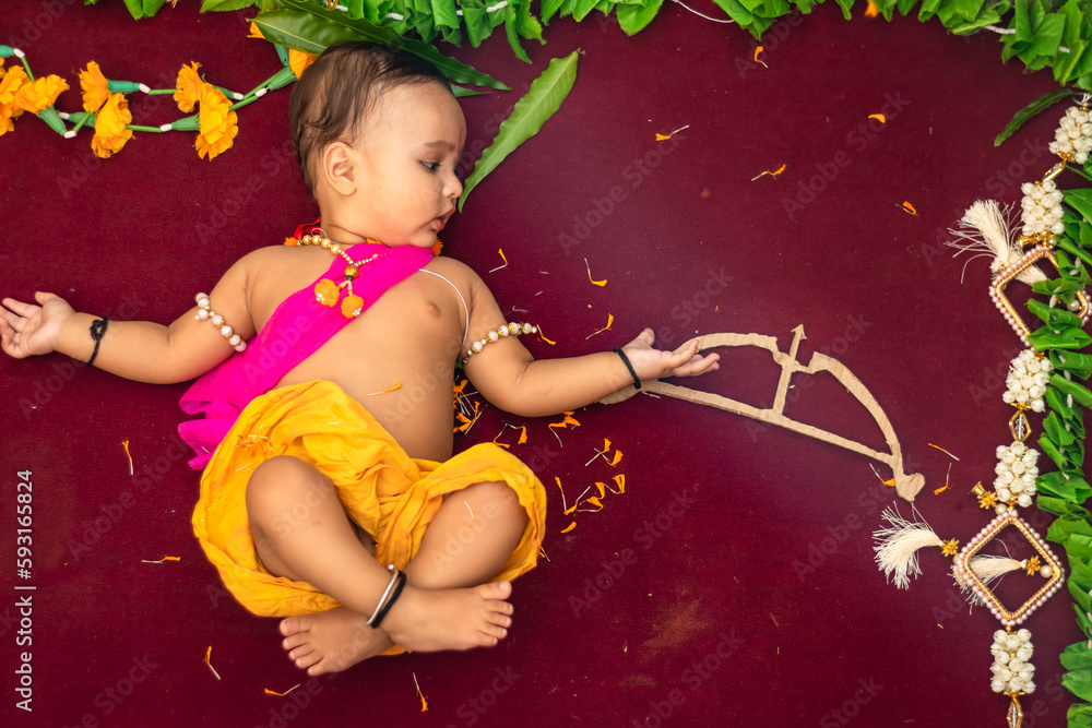 cute Indian boy dresses as lord rama with bow and flowers from top angle - obrazy, fototapety, plakaty 