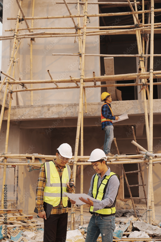 Team of engineer and worker checking construction site outdoors Surveyor builder Engineer surveying work checking schedule for rebuilding project. Team of engineer and worker checking construction site outdoors Surveyor builder Engineer surveying work checking schedule for rebuilding project.