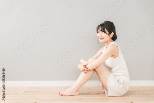 フローリングに座る笑顔の美しいアジア人女性（美容・スキンケア・ダイエット） 