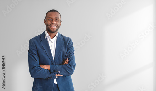 Confident African businessman with crossed arms, white