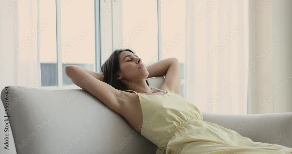 Relaxed peaceful beautiful girl resting on comfortable sofa at home, leaning on back, holding head, sleeping, waking up, opening eyes, looking at window away, smiling, enjoying leisure, relaxation Relaxed peaceful beautiful girl resting on comfortable sofa at home, leaning on back, holding head, sleeping, waking up, opening eyes, looking at window away, smiling, enjoying leisure, relaxation