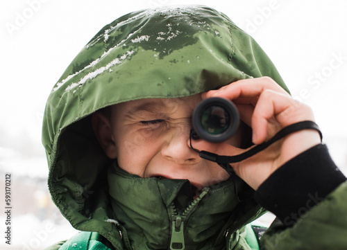 close up portrait of boy looking through a telescope photo