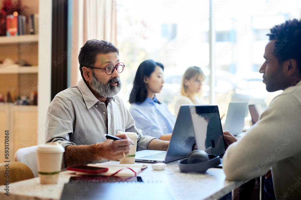 Mature businessman explaining coworker during meeting in cafe Mature businessman explaining coworker during meeting in cafe