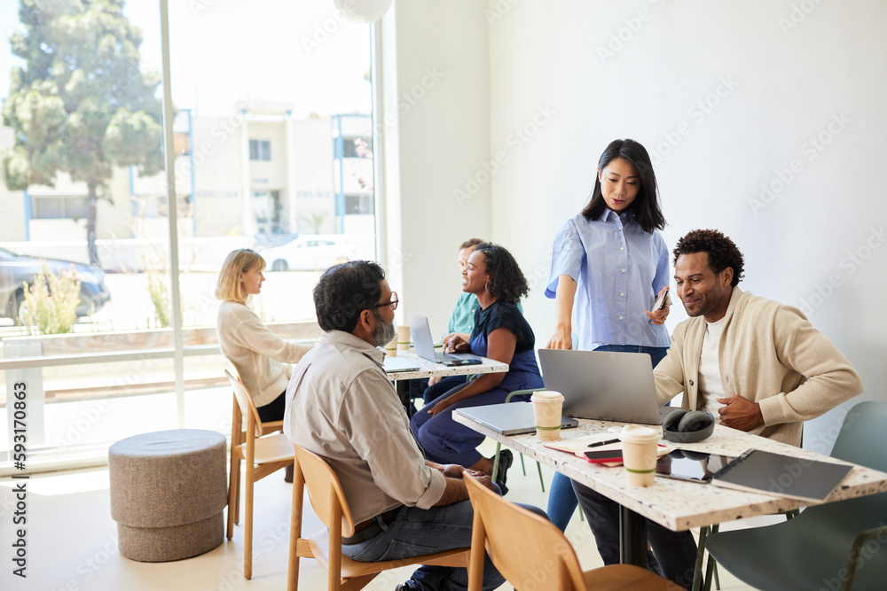 Businesswoman explaining male coworker over laptop in coffee shop Businesswoman explaining male coworker over laptop in coffee shop