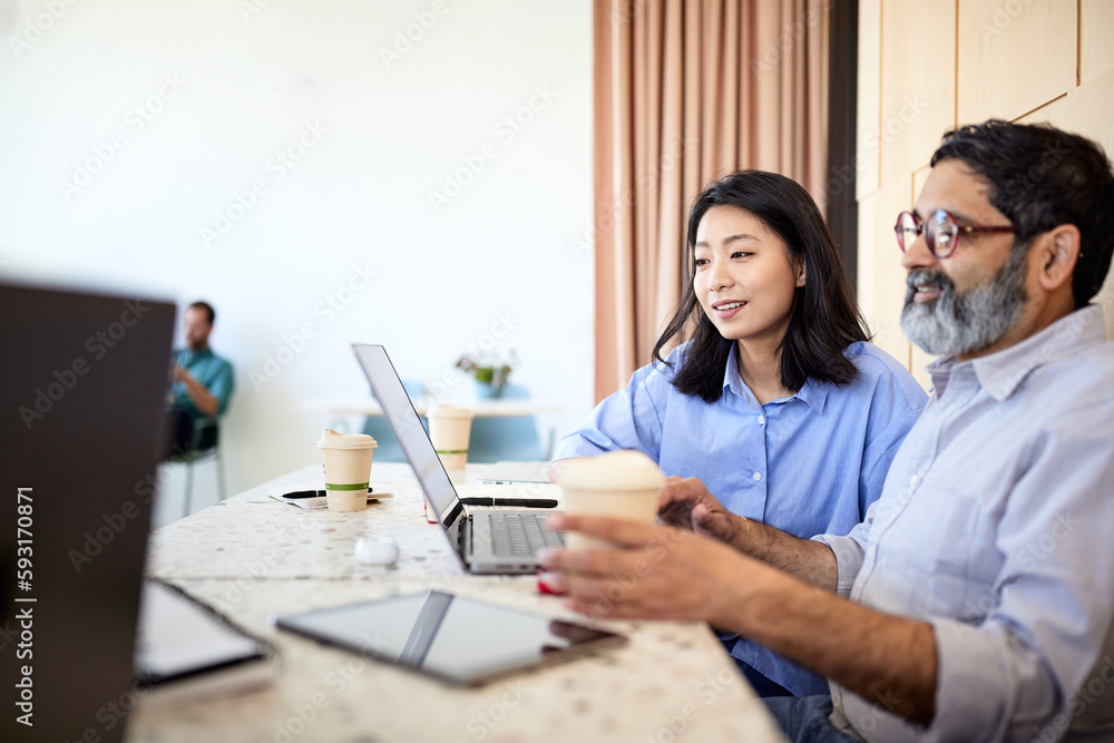Businesswoman sharing laptop with coworker sitting in coffee shop Businesswoman sharing laptop with coworker sitting in coffee shop