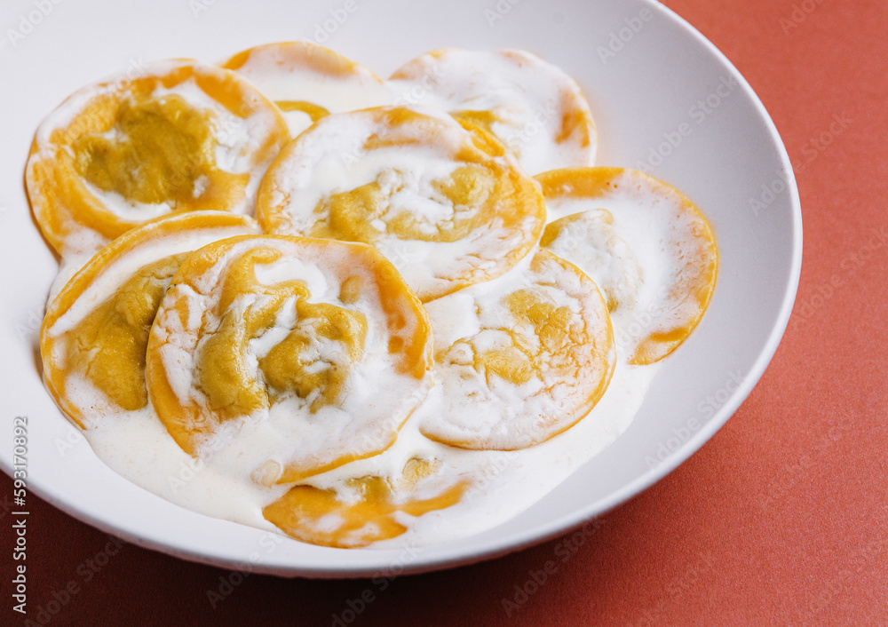 Boiled ravioli with sour cream on plate Boiled ravioli with sour cream on plate
