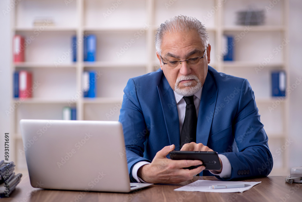 Old male employee working in the office Old male employee working in the office