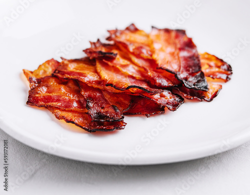 Plate with tasty bacon slices on stone