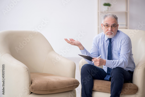 Old male psychologist sitting in the room