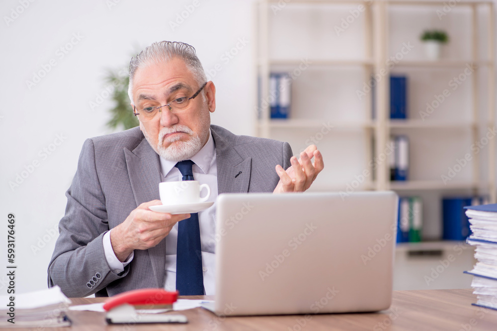Old male employee drinking coffee during break